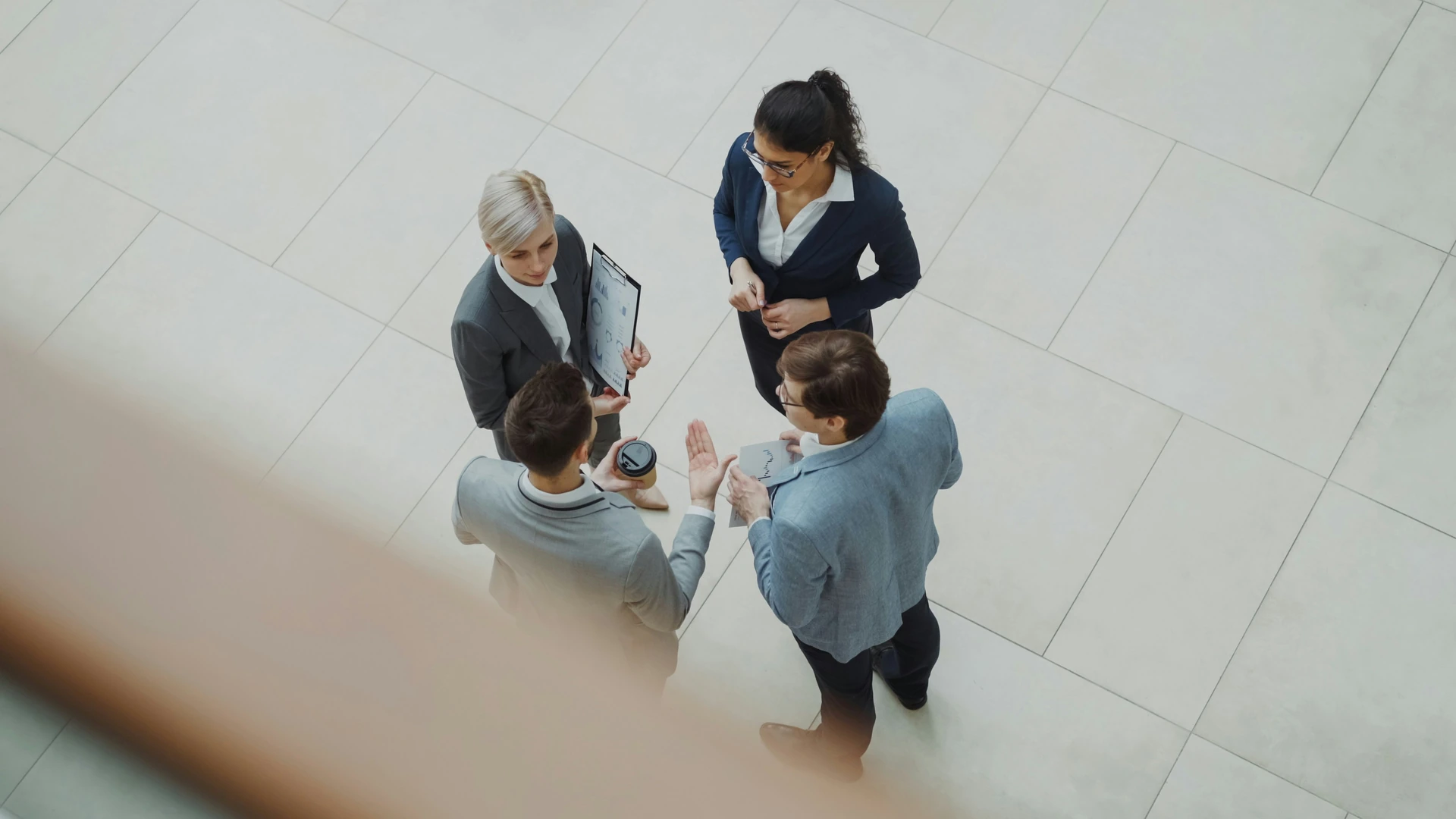 Four business professionals talking in an office atrium