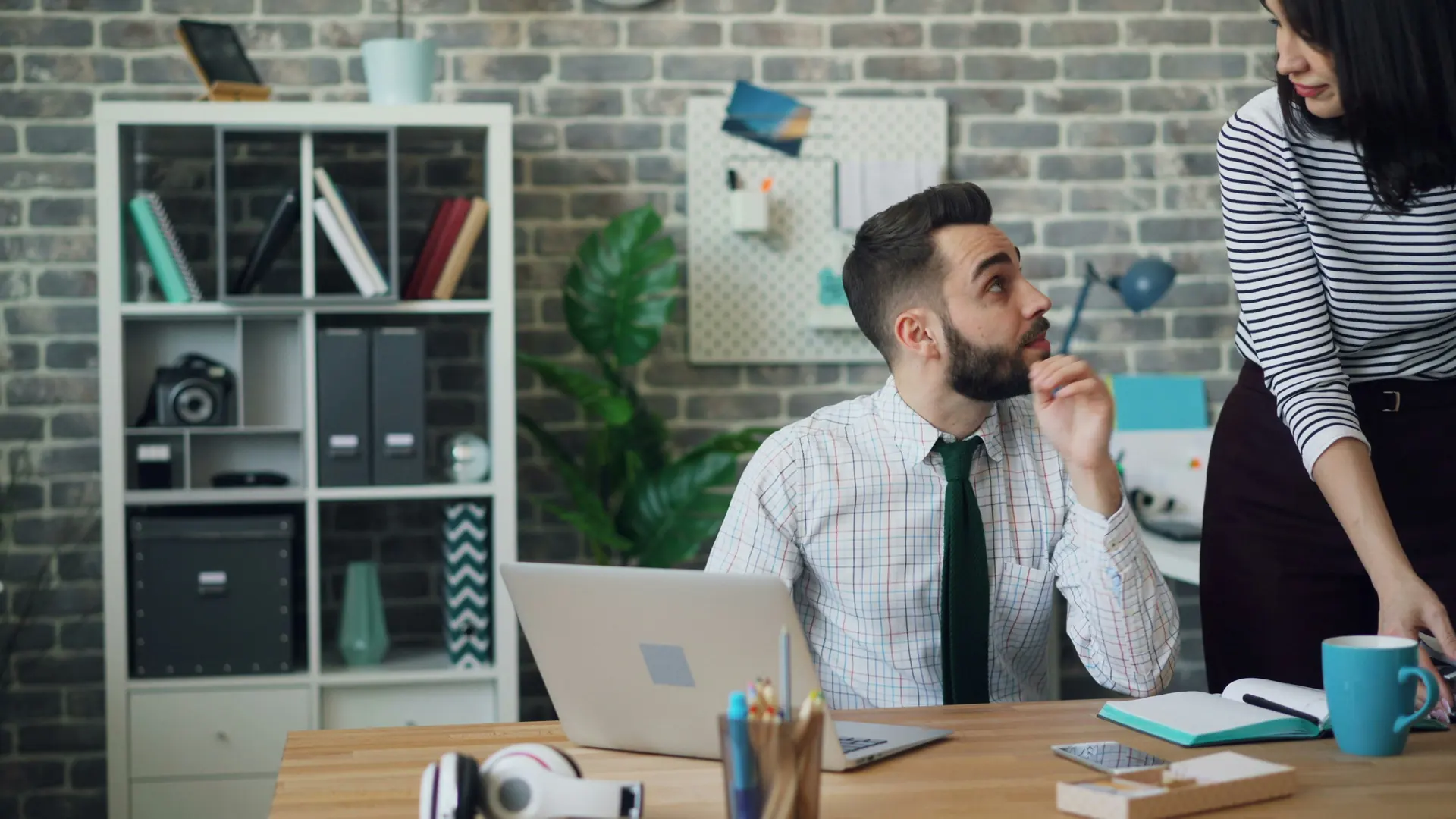 Two colleagues discussing work beside a laptop