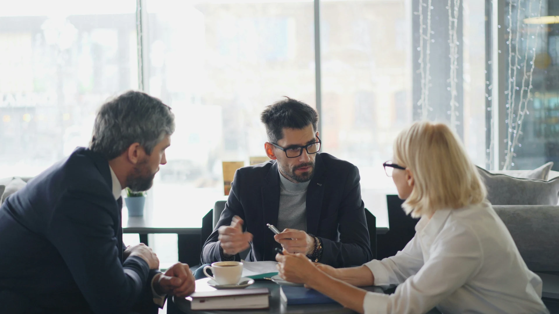 Three people discussing documents at a table